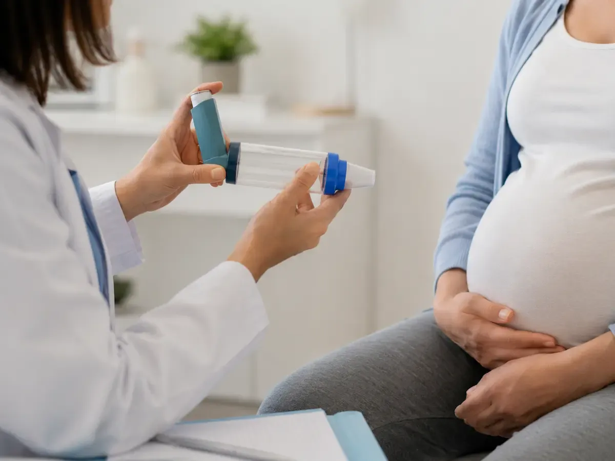 Revisar la técnica de inhalación es clave: gran parte del "mal control" se debe solo a usar mal el inhalador. Profesional sanitaria muestra a una embarazada cómo usar el inhalador con cámara espaciadora en consulta.